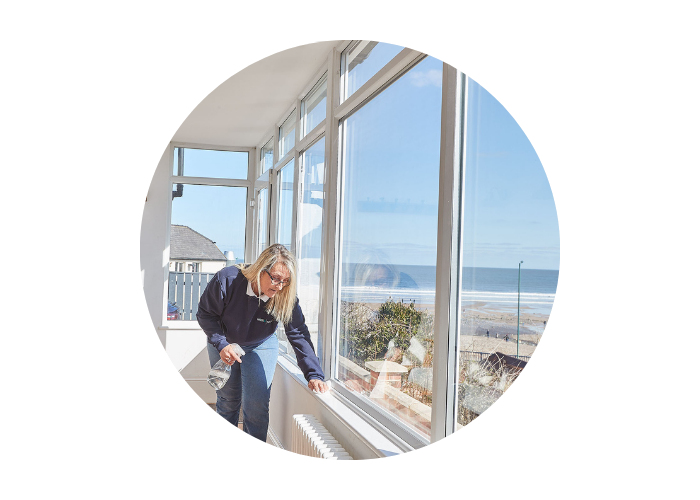 The image shows a Host & Stay housekeeper cleaning the sunroom in Burnsyde Beach House in Saltburn-by-the-Sea. 