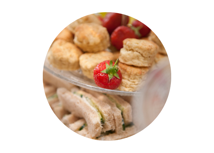 An up close image of afternoon tea including scones, strawberries and finger sandwiches. 