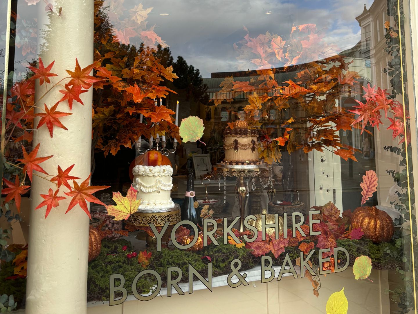 A view of the window display at Mama Doreen's in Harrogate. The window has autumn leaves and says 'Yorkshire Born & Baked'.