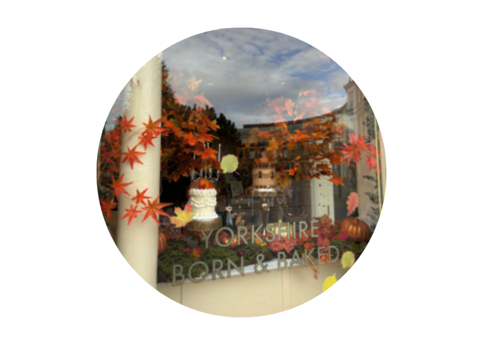 A view of the window display at Mama Doreen's in Harrogate. The window has autumn leaves and says 'Yorkshire Born & Baked'.