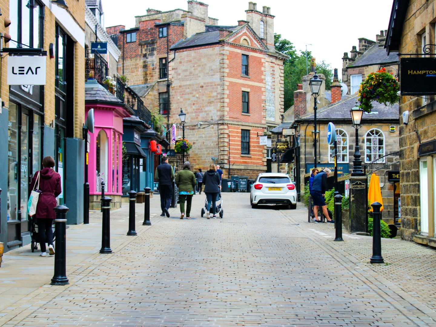 A view of The Montpellier Quarter in Harrogate. The image shows a cobbled street lined with boutiques on either side and people walking up the road.