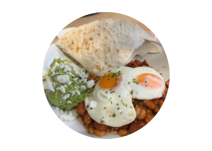 An image of the baked eggs served at Weetons in Harrogate. It includes a flat bread, guacamole, fried eggs and beans.